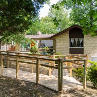 A house surrounded by trees with a wooden ramp leading to the entrance.