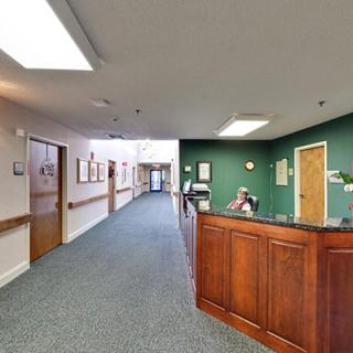 A reception desk in an office hallway with green walls and carpeted flooring.