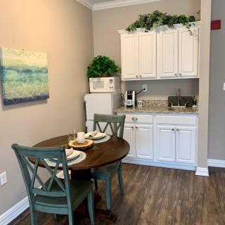 Cozy kitchen corner with a small dining table and chairs, white cabinets, and decorative accents.