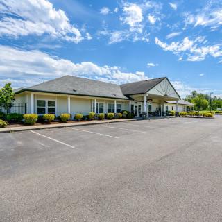 A spacious building with a large parking lot under a partly cloudy sky.