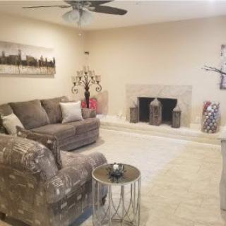 A cozy living room with a sofa, armchair, and fireplace.