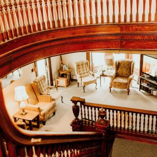 A cozy living room with a classic wooden staircase and comfortable armchairs.