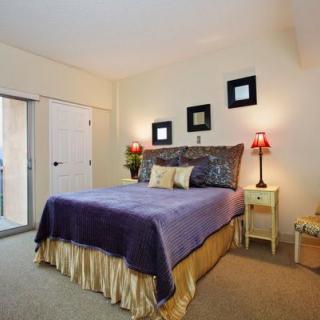 A cozy bedroom with a neatly made bed, accented by decorative pillows and nightstands with lamps.