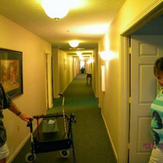 An elderly person using a walker in a well-lit hallway.