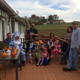 A joyful family gathering celebrating autumn with costumes and pumpkins.