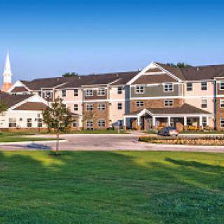 A modern residential building with a landscaped lawn and clear blue sky.