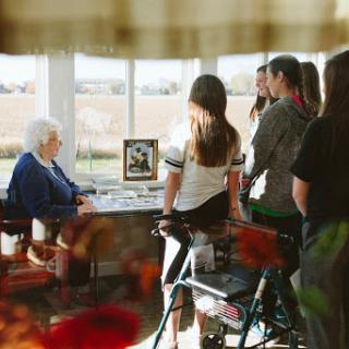 A touching moment as family members visit an elderly individual, sharing stories and memories in a sunlit room.