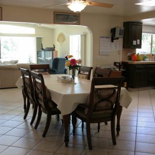 A spacious dining room with a large table and chairs, connected to a kitchen and living area.