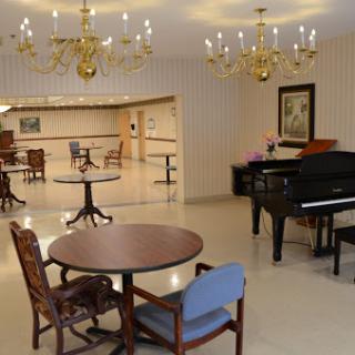 A spacious lounge area featuring elegant chandeliers and a piano, designed for relaxation and social gatherings.