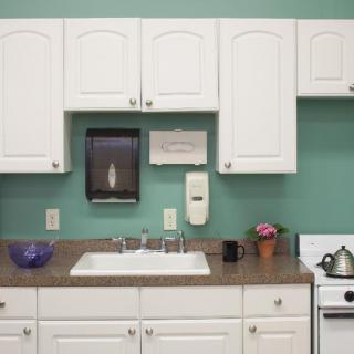 A kitchen setup featuring white cabinets, a sink with a countertop, and a teal painted wall.