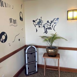A retro-themed corner with wall art of musicians, vinyl records, a jukebox, and an indoor plant.