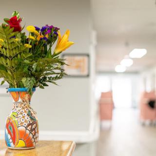 A colorful bouquet of flowers in an artistic vase brightens up a hallway.
