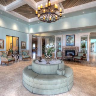 A spacious and elegant living room featuring a central round sofa, a chandelier, and tasteful decor.