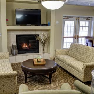 A cozy living room setting featuring a fireplace, comfortable seating, and a television.
