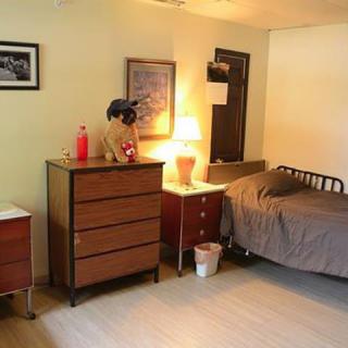 A cozy bedroom with a bed, dresser, and warm lighting.