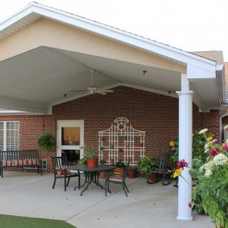 A cozy covered patio with outdoor furniture and decorative plants.