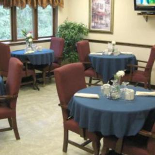 A cozy dining room with several tables and chairs, each table covered with a blue tablecloth.