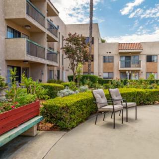 A well-maintained apartment complex with outdoor seating and lush landscaping.