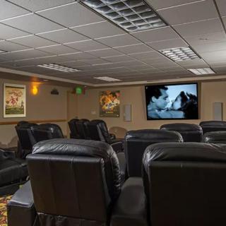 A cozy home theater with multiple leather seats facing a large screen.