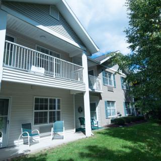 A two-story residential building with a balcony and lawn area.