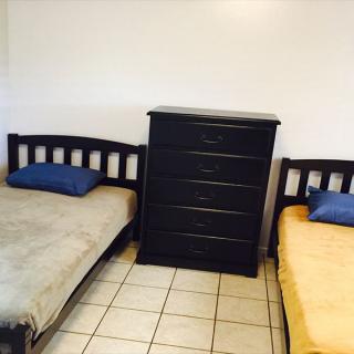 A bedroom with two single beds and a central dresser.