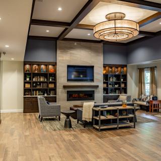 A modern living room with a fireplace, elegant chandelier, and comfortable seating.