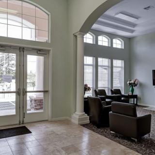 A modern lobby with large windows, armchairs, and a television.