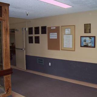 A hallway with plaques and a bulletin board on the wall.