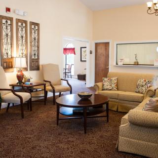 A cozy and elegantly decorated living room with comfortable sofas and chairs, centered around a coffee table on a plush carpet.