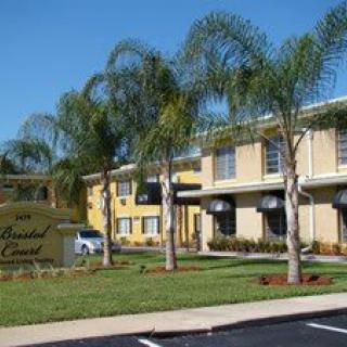 A sunny view of a hotel surrounded by palm trees and well-maintained landscaping.