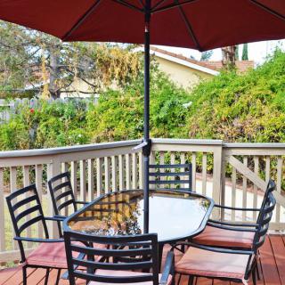 A patio set with a table and chairs under a large umbrella on a wooden deck.