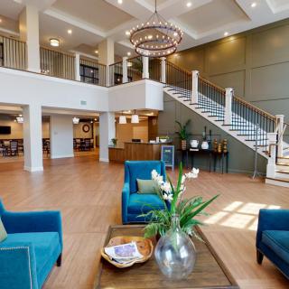 A modern and spacious lobby featuring comfortable seating, elegant decor, and a grand staircase.