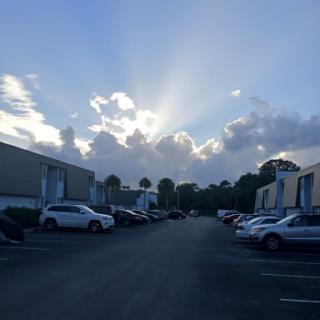 A serene view of a parking lot under a bright sky with rays of sunlight breaking through the clouds.