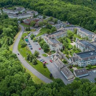Aerial view of a building complex surrounded by lush greenery and forested areas.