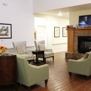 A cozy living room with a fireplace, comfortable seating, and a wall-mounted television.