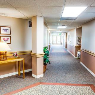 A well-lit hallway in an office building with carpeted flooring and simple decor.