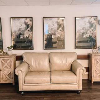 A cozy living room setup with a beige sofa flanked by wooden cabinets and abstract artwork on the wall.