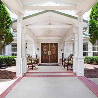A welcoming entrance to a building with seating and greenery.