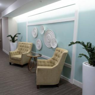 A cozy lobby seating area with two tufted chairs and decorative wall art.