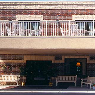 A brick building with a balcony featuring outdoor furniture.