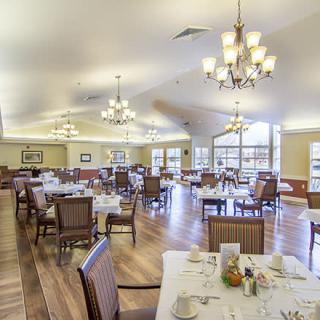 An elegant dining room with neatly arranged tables and warm lighting.