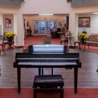 A grand piano situated in an elegantly decorated lobby with floral arrangements.
