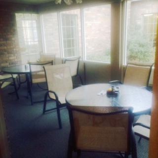 A cozy dining area with round tables and chairs near large windows.