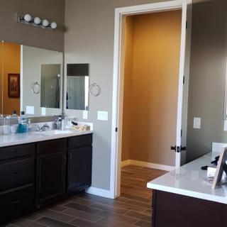 A modern bathroom featuring a large mirror above the vanity with dual sinks and bright lighting.