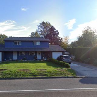 A suburban house with a well-maintained lawn and driveway on a sunny day.