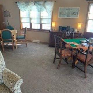 Cozy living and dining area with carpeted flooring and a mix of furniture.