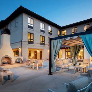 A serene hotel courtyard with comfortable outdoor seating and a cozy fireplace, perfect for evening relaxation.
