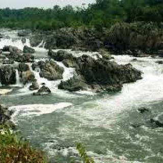 A scenic view of a river with cascading waterfalls and surrounding greenery.