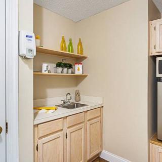A compact kitchen nook with wooden cabinets, a small sink, and decorative shelves.