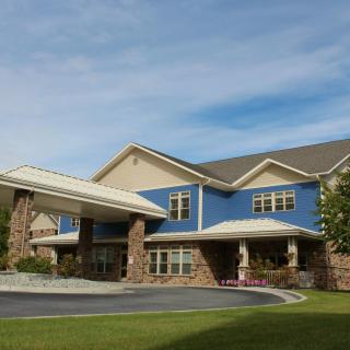 A large, modern residential building with a blue and beige exterior and stone accents on a sunny day.